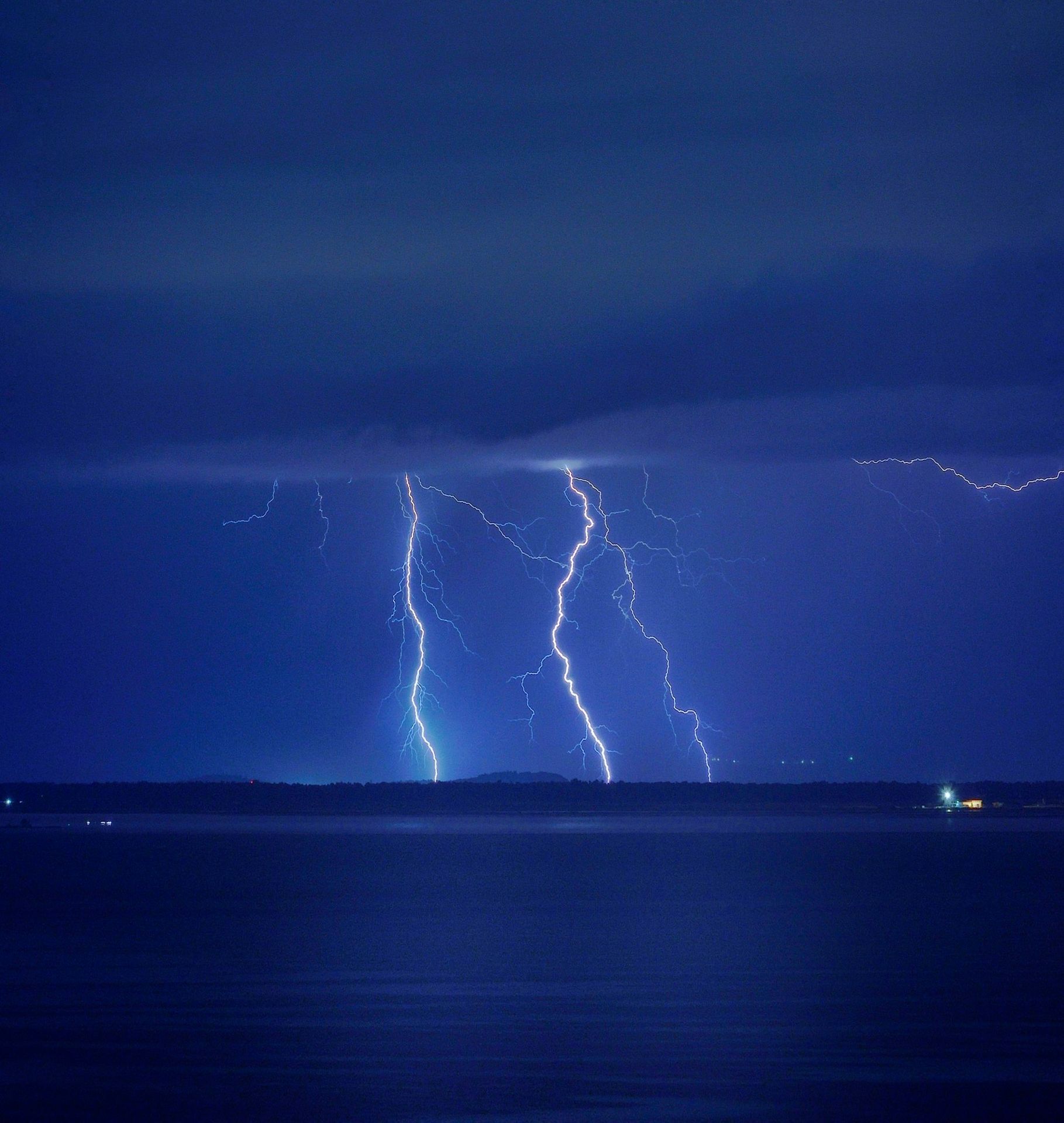 a couple of lightning strikes over a body of water